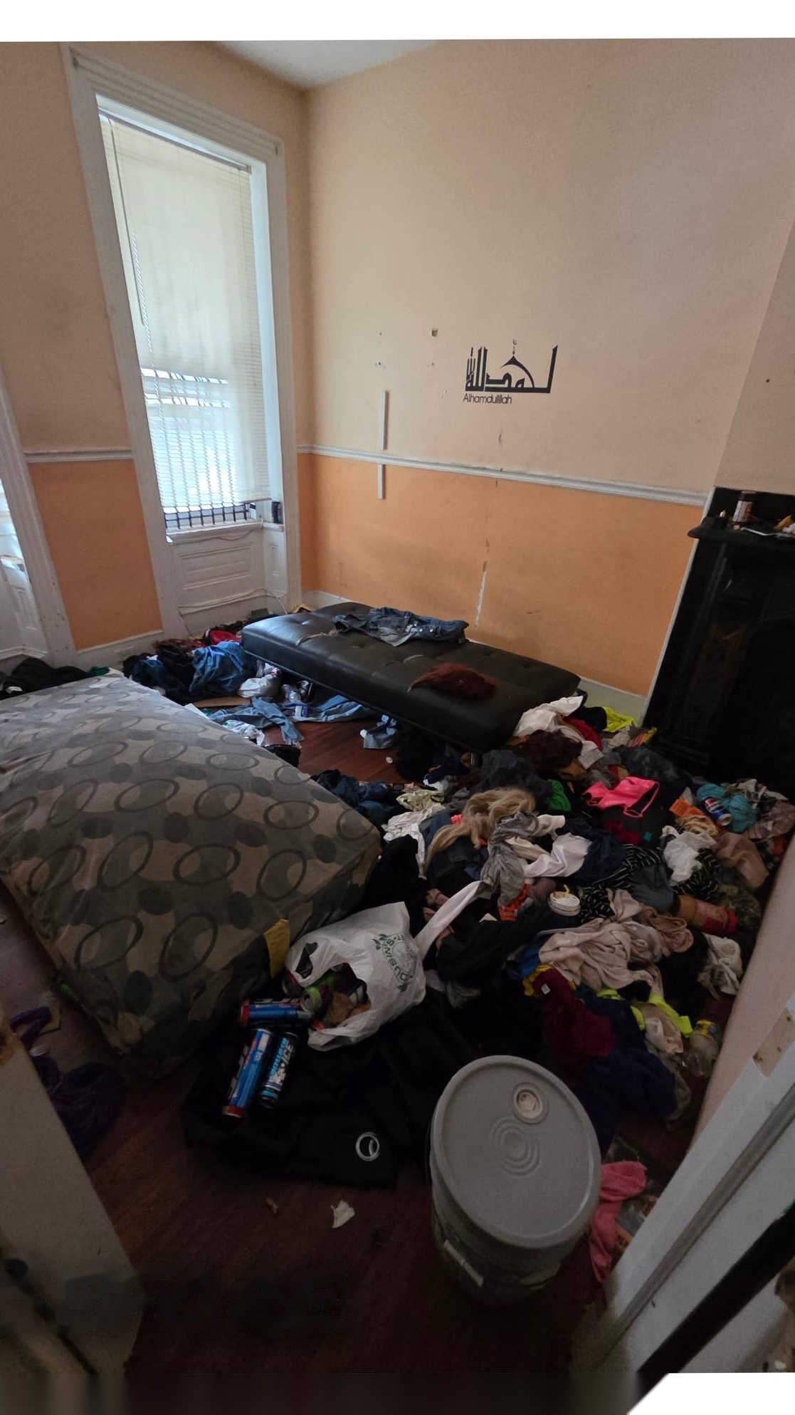 Bedroom covered in clothes and debris before cleanout